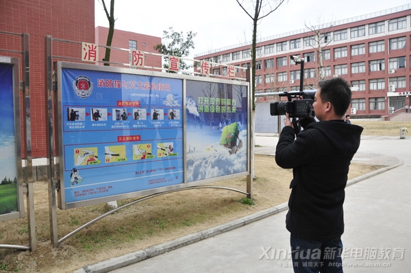 合肥市新闻中心工作人员正在拍摄安徽新华电脑专修学院消防安全栏